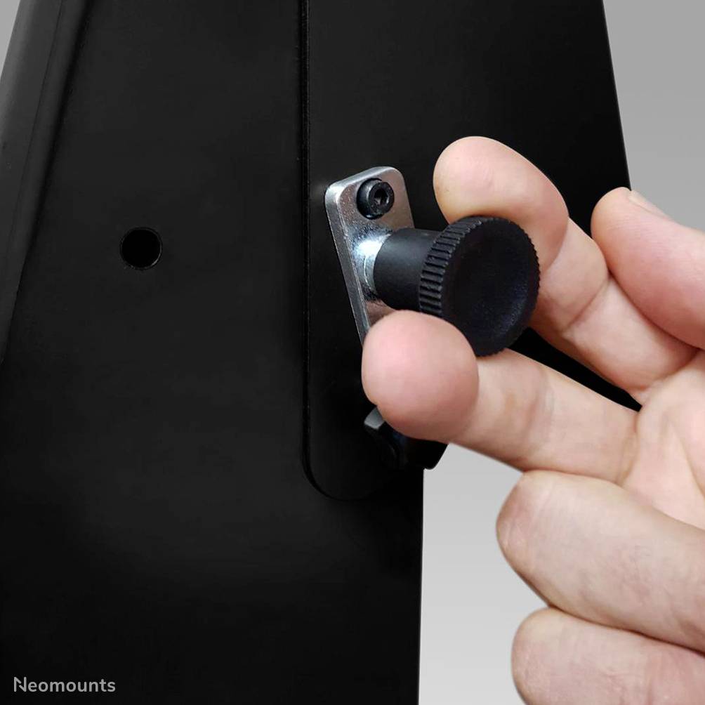 Eine Hand dreht eine Einstellschraube an einem schwarzen Gerät, um die Position oder Spannung zu verändern.