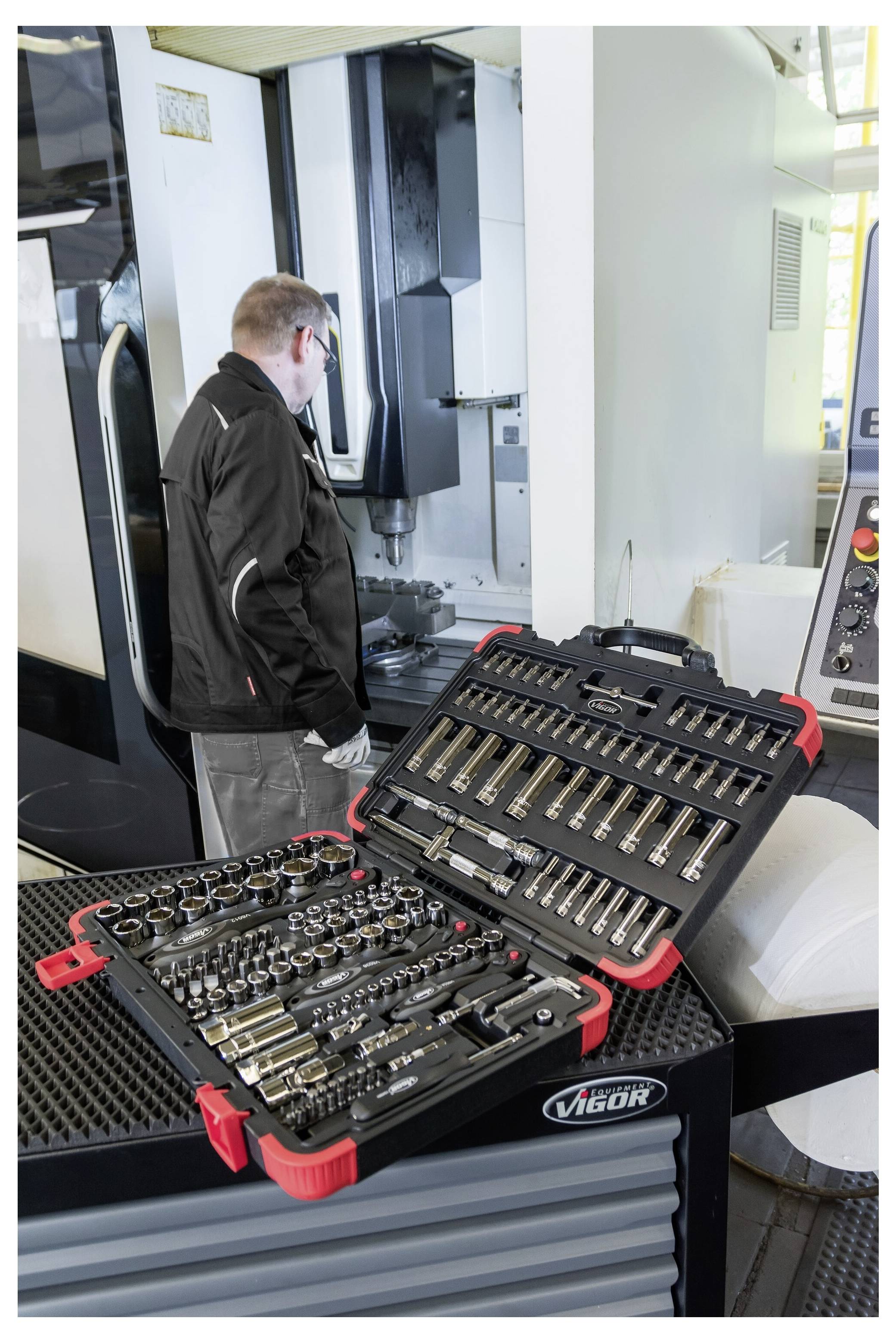 Techniker neben einer CNC-Maschine mit offenen Werkzeugkoffern auf einem Shopwagen, die einen organisierten Satz von Metallschneidwerkzeugen und Haltern zeigen.