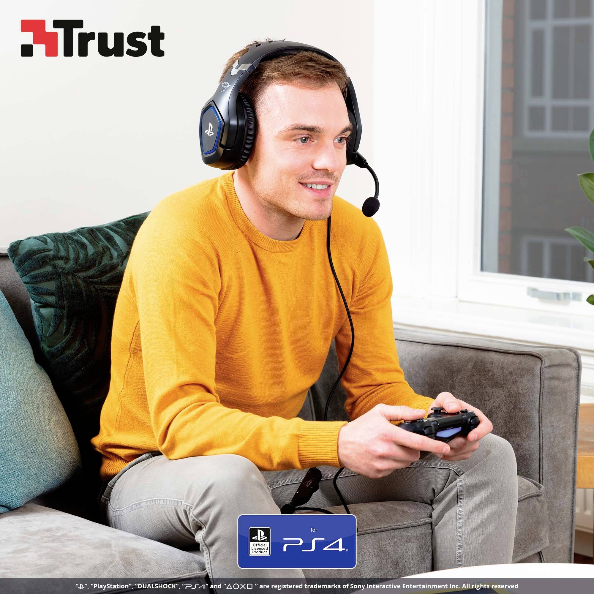 Ein Mann mit Headset sitzt auf einem Sofa, hält einen Controller und schaut auf einen Bildschirm. 'Trust'-Logo oben links.