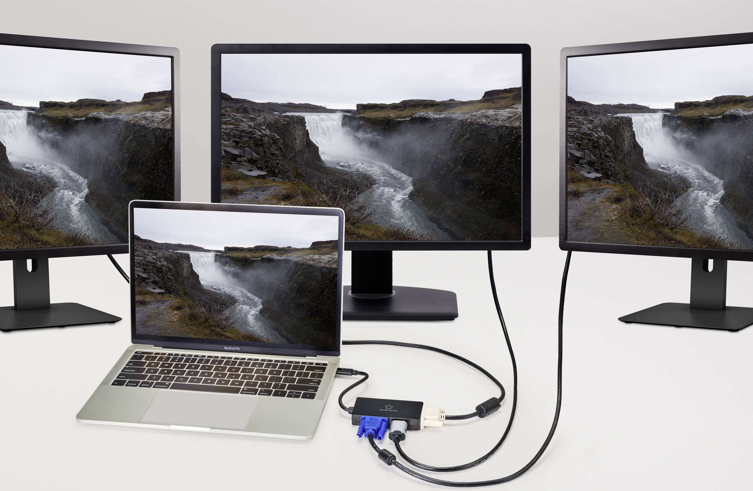 Ein Laptop ist mit zwei Monitoren verbunden, die denselben Flusslandschaft-Bildschirmhintergrund zeigen, verbunden über Adapter und Kabel.