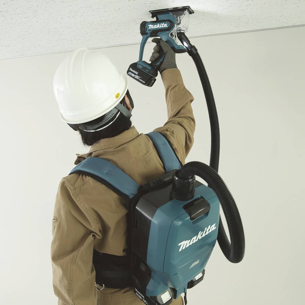 Eine Person verwendet eine Makita Trockenbauschleifmaschine an einer Decke und trägt dabei einen Schutzhelm und einen rückentragenartigen Staubsauger für Sicherheit und Effizienz.