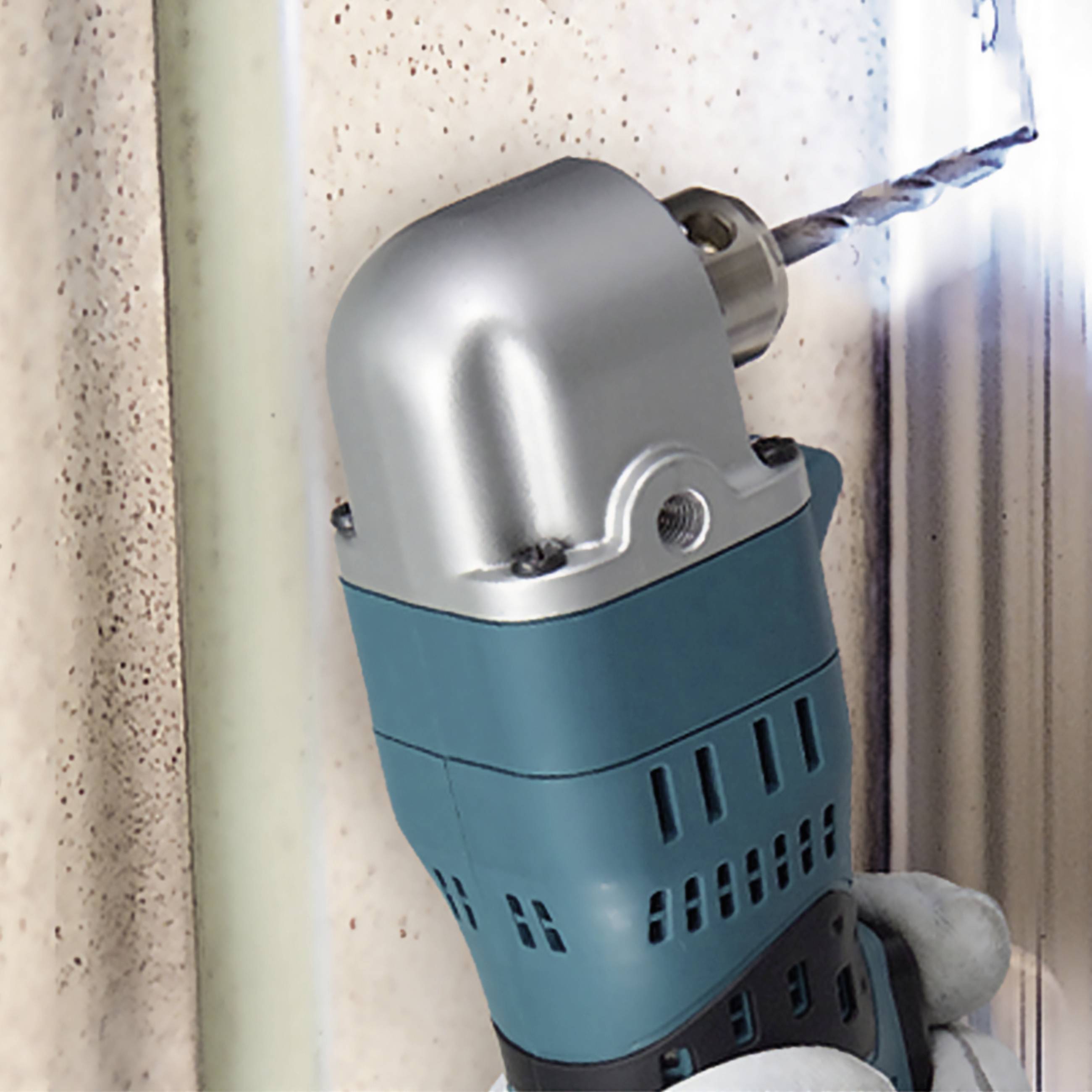 Eine blaue Bohrmaschine bohrt ein Loch in eine beige Wand, Staubpartikel sind sichtbar.