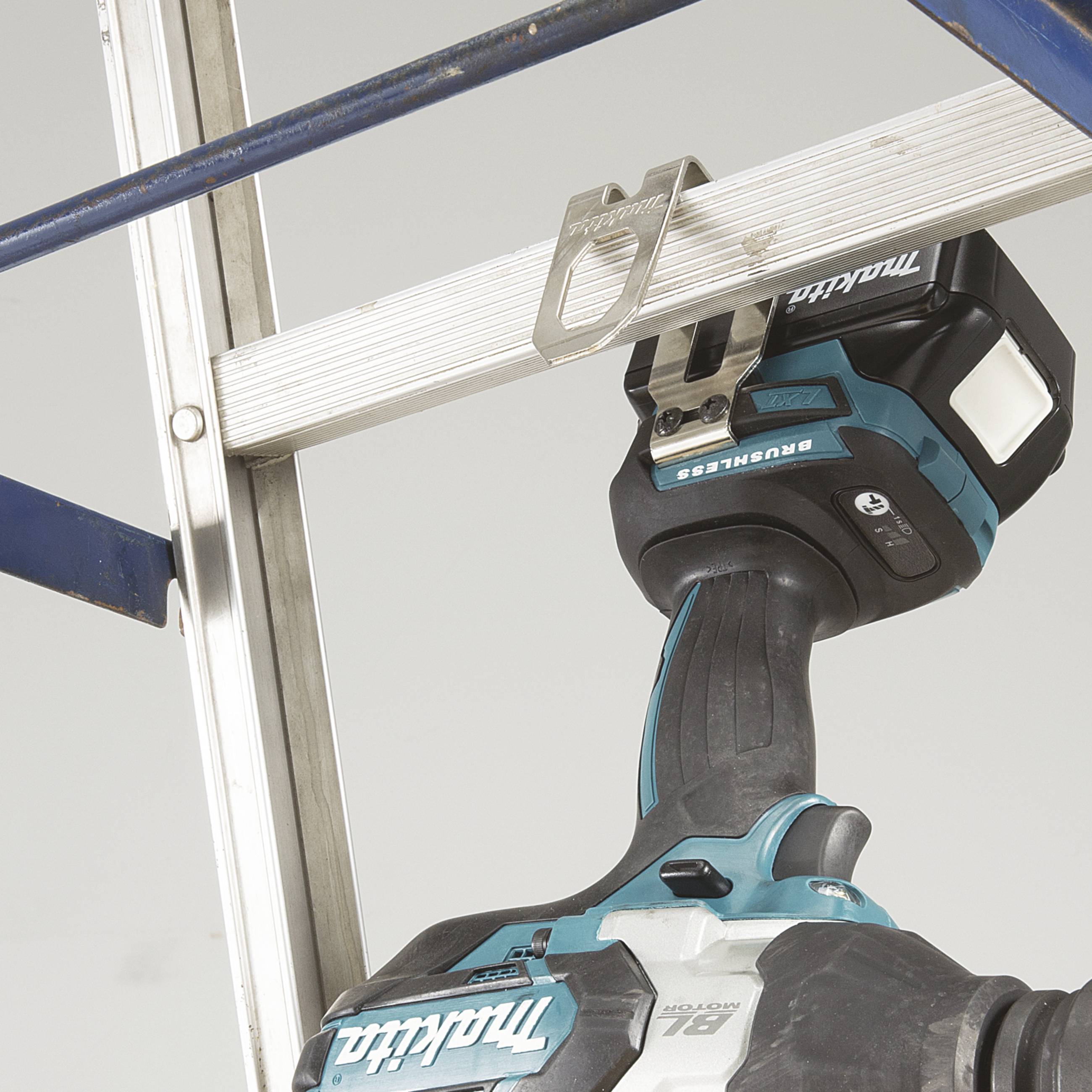 Ein schwarzer Akkubohrer der Marke Makita hängt an einem silbernen Aluminiumgestell.