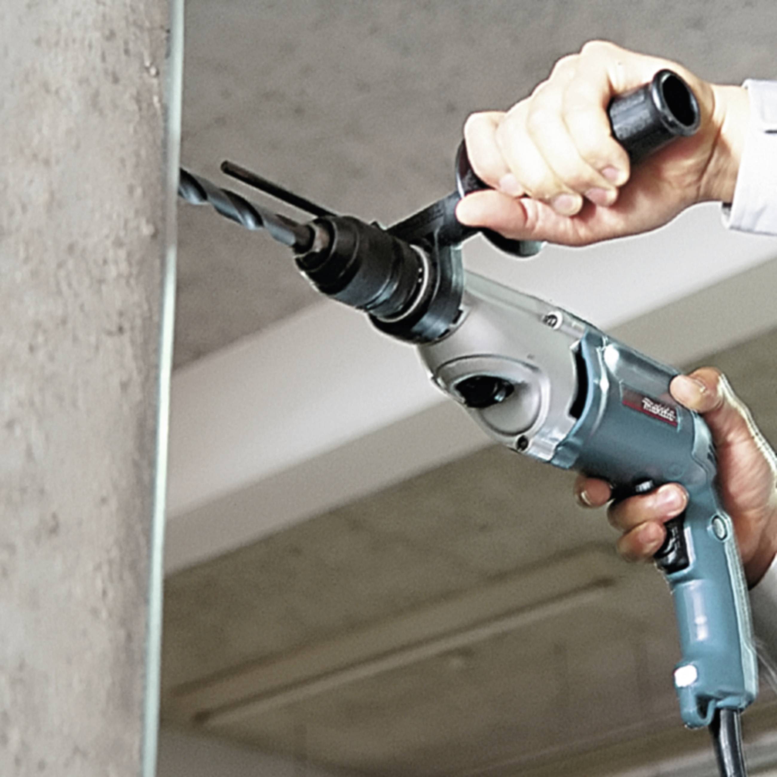Eine Person bohrt mit einer elektrischen Bohrmaschine ein Loch in eine Wand.