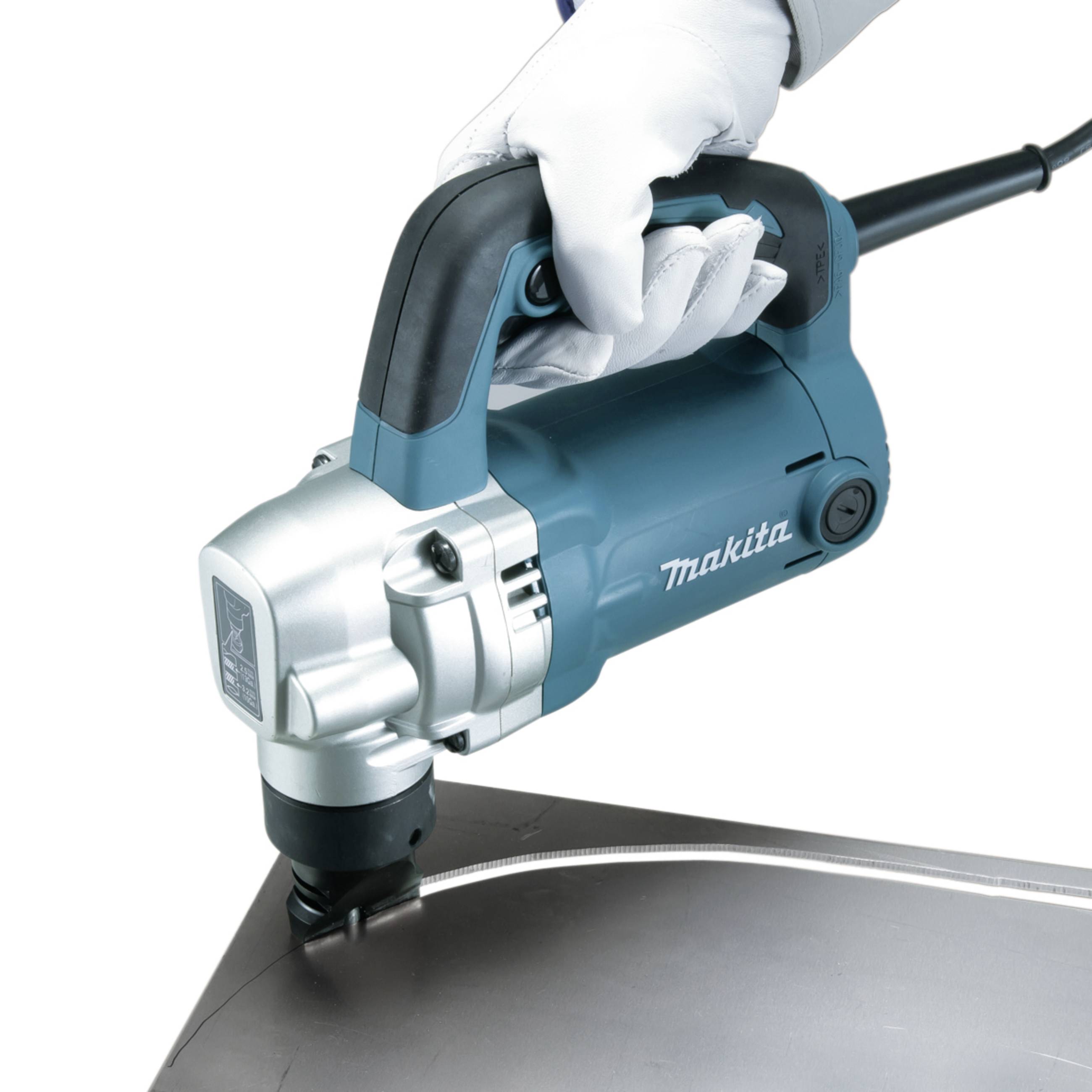 Eine Hand führt ein Makita-Elektrowerkzeug, das ein großes Metallblech schneidet. Das Werkzeug ist blau mit einem silbernen Kopf.