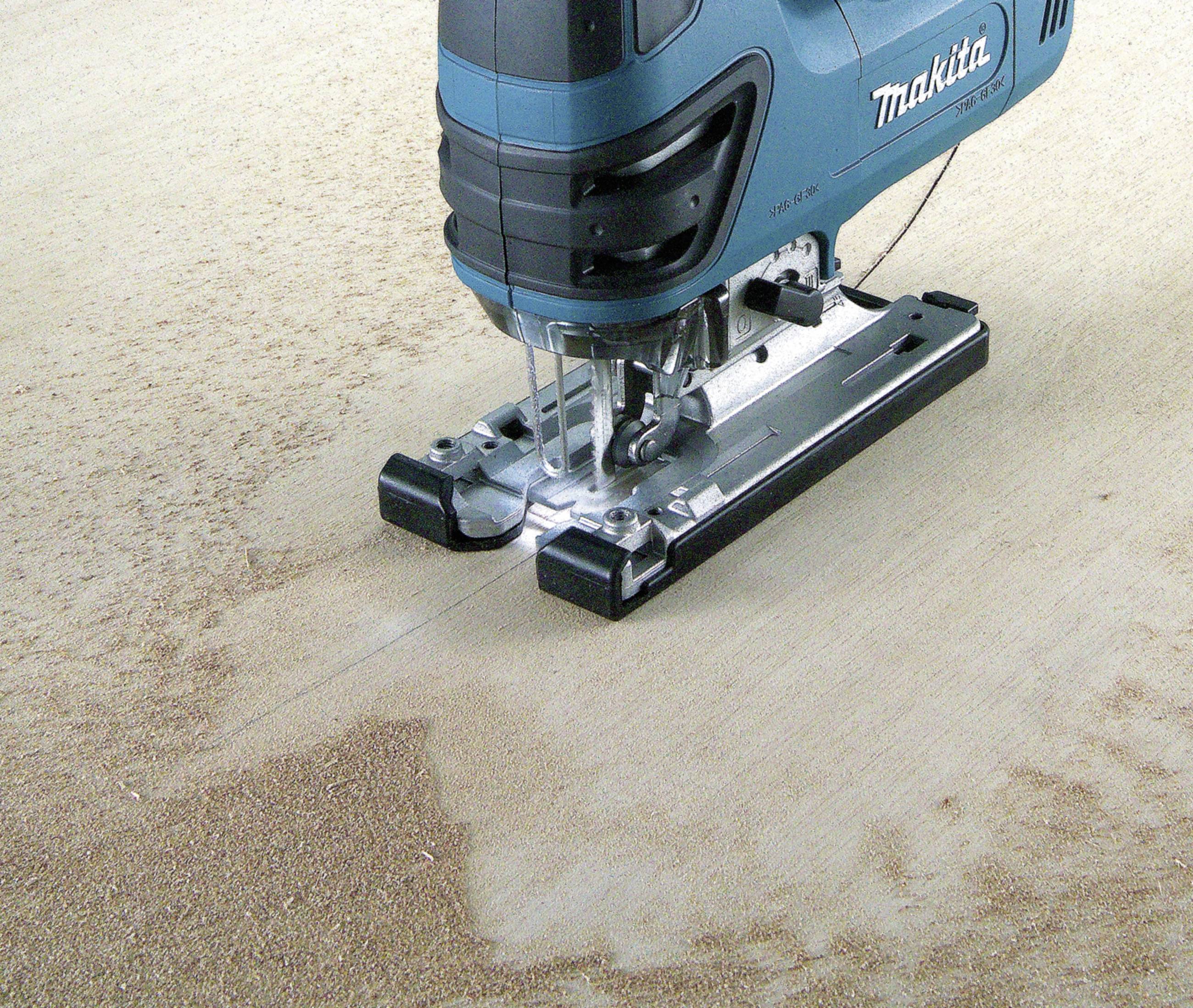 Eine blaue Stichsäge schneidet Holz entlang einer markierten Linie auf einer Werkbank. Sägemehl umgibt die Schnittstelle.