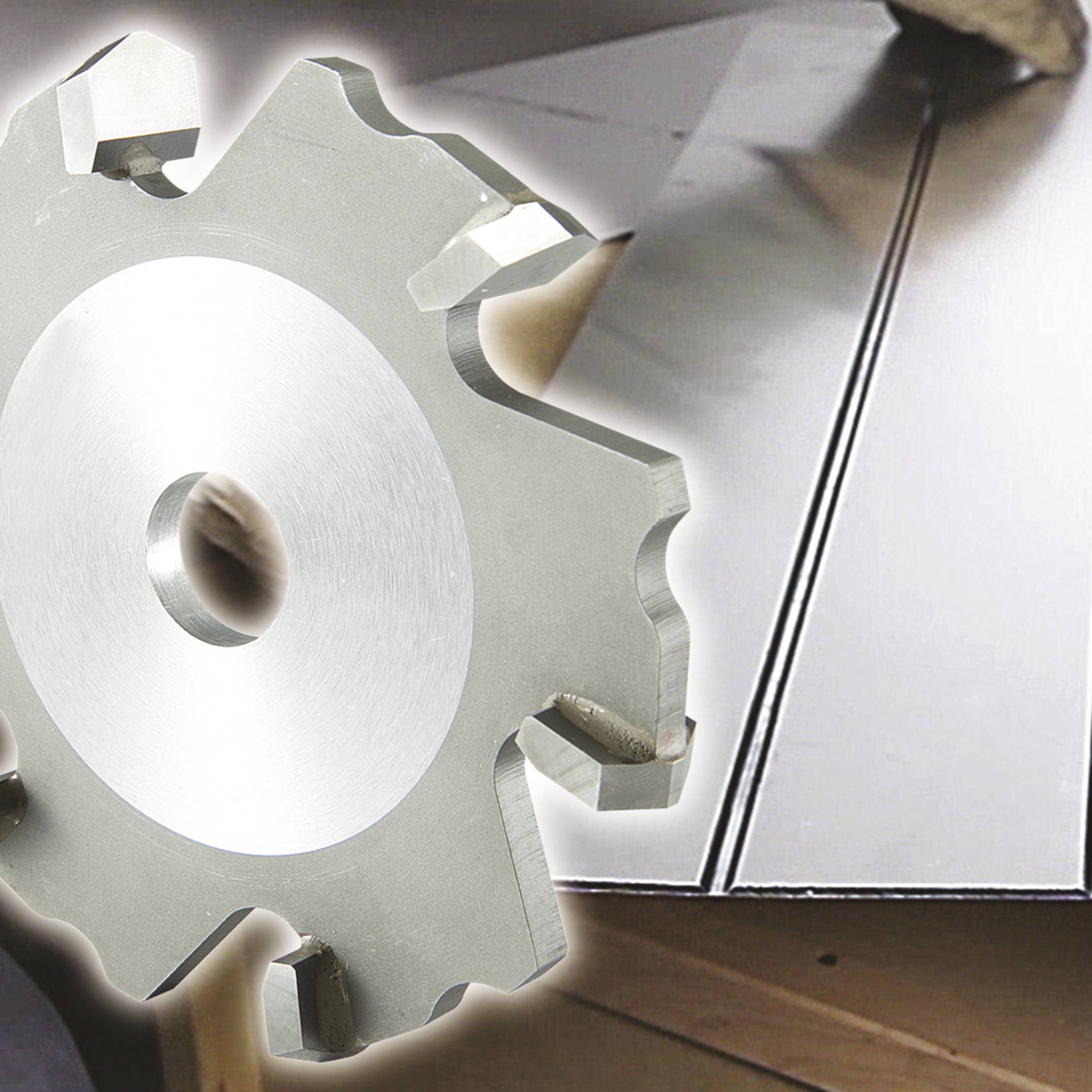 Nahaufnahme eines kreisförmigen Fräsers vor einem Hintergrund mit Metallplatten. Der Fräser zeigt Zähne und eine Bohrung in der Mitte.