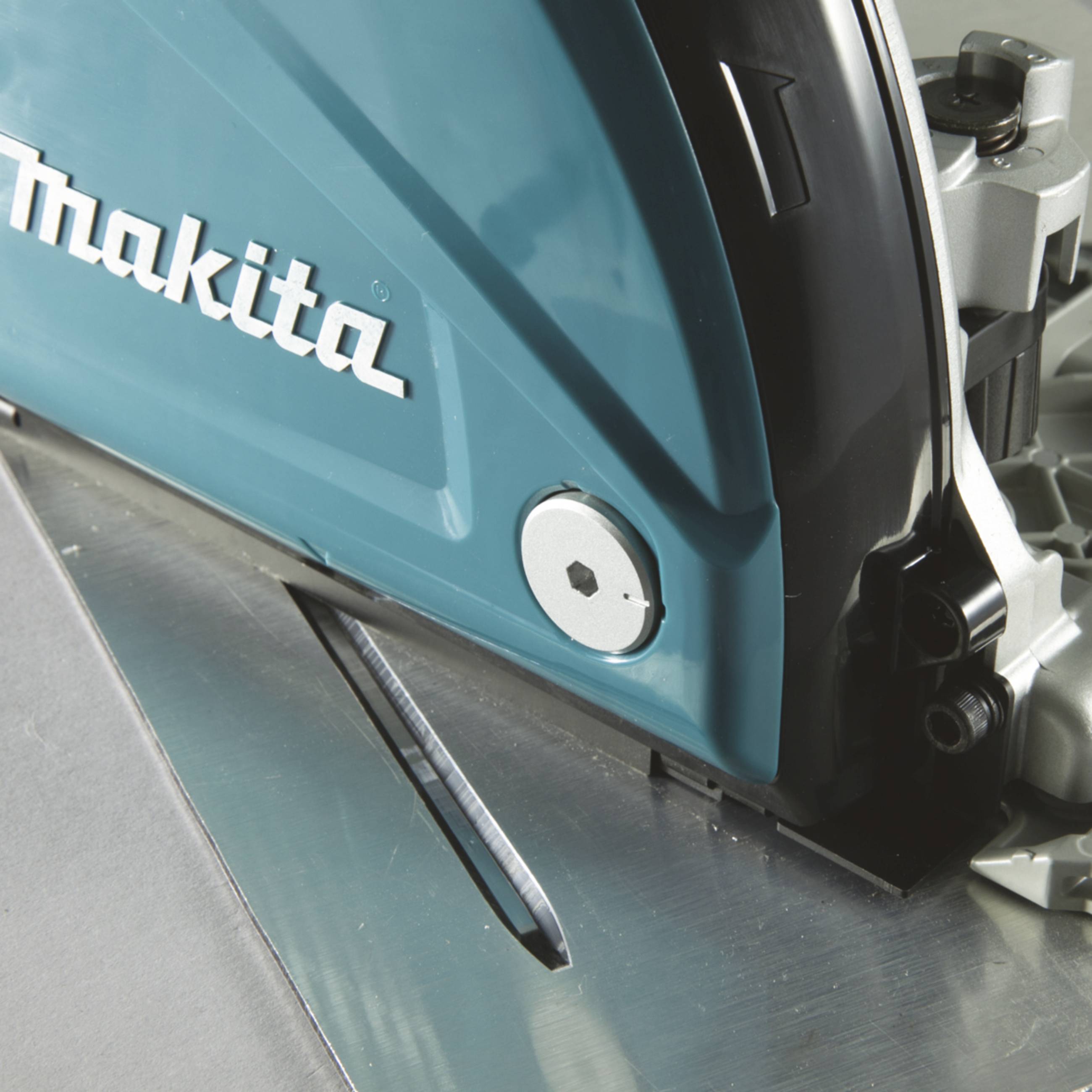 Eine Kreissäge in Nahaufnahme mit sichtbarem Sägeblatt und blauem Gehäuse, auf dem 'Makita' steht. Gerät in Aktion auf Metalloberfläche.
