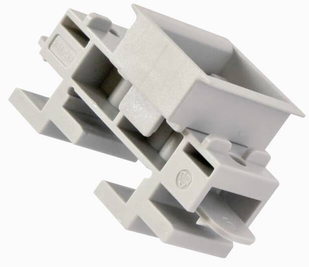 Ein graues, rechteckiges Kunststoffteil, möglicherweise ein Bauelement oder Verbinder, mit Haken und Ausbuchtungen an den Seiten.