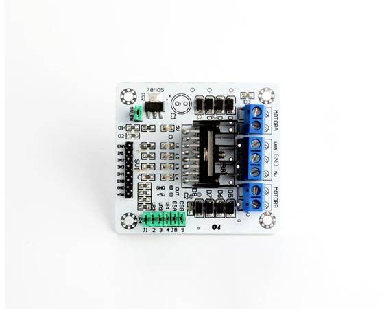 Eine weiße Platine mit mehreren schwarzen und blauen Anschlüssen sowie grünen Anschlusspunkten. Geeignet für elektronische Schaltungen.