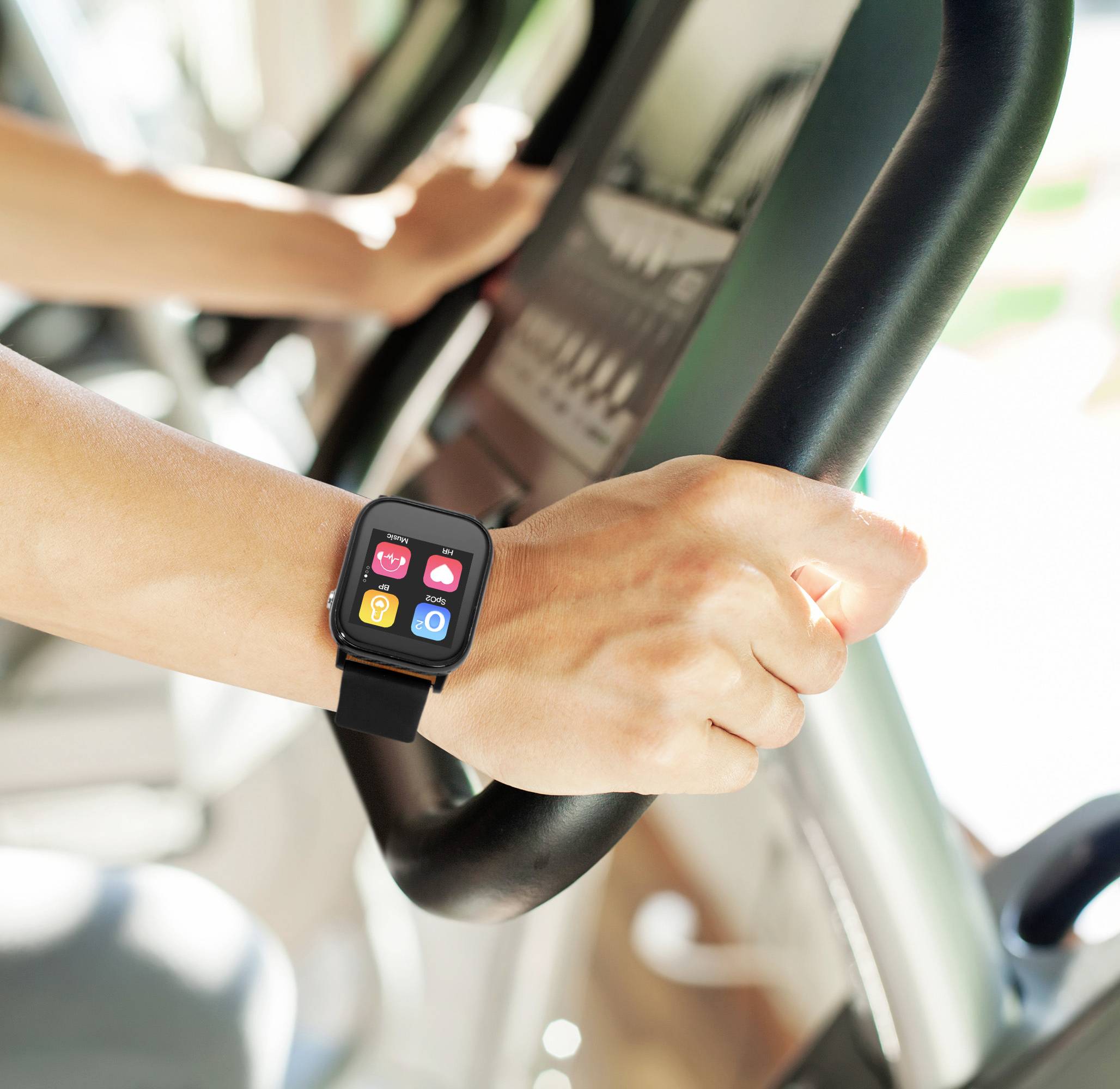 Eine Person trainiert auf einem Fitnessgerät und trägt eine Smartwatch am Handgelenk, die bunte Apps auf dem Display zeigt.