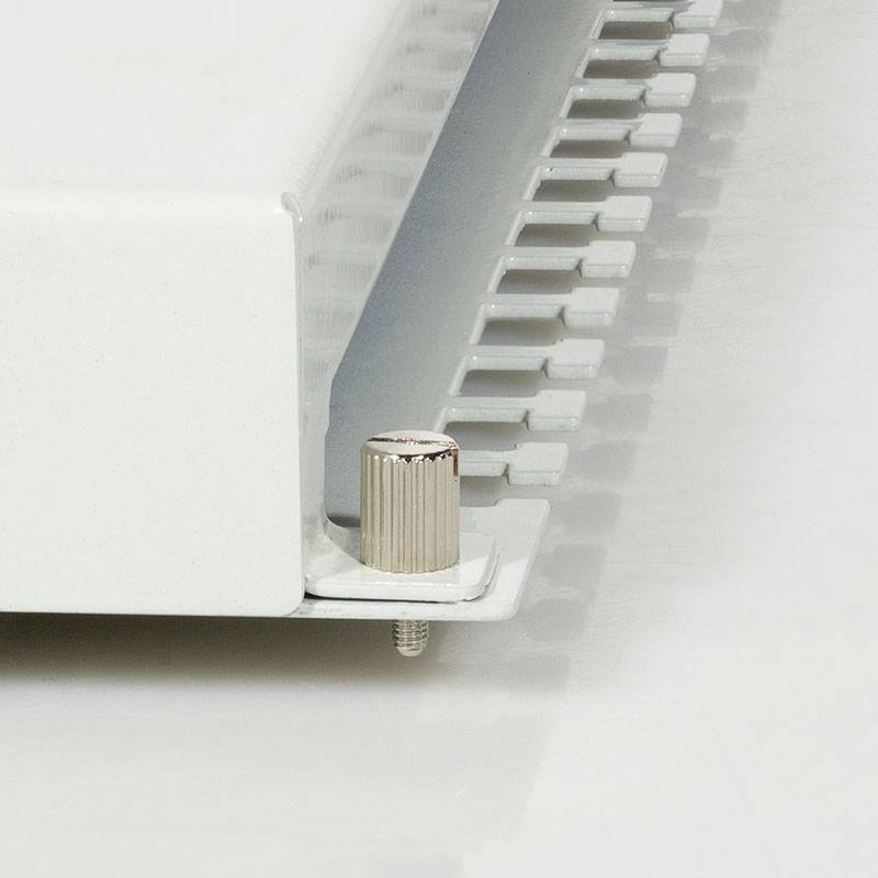 Ein weißer Heizkörper mit einem Temperaturregler an der Seite, der in einem Raum montiert ist. Der Regler ermöglicht die Wärmeeinstellung.