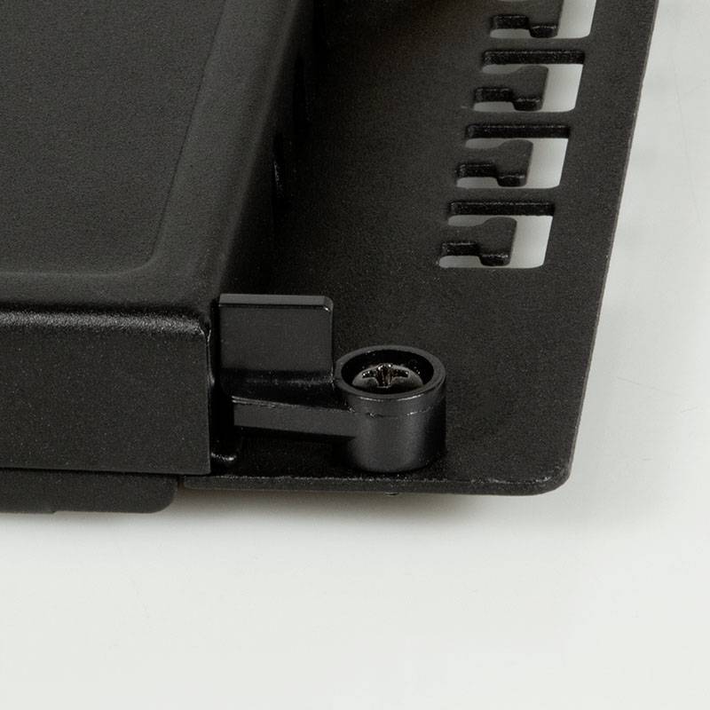 Nahaufnahme eines schwarzen, rechteckigen Geräts mit Befestigungsschraube, das auf einer Halterung montiert ist.