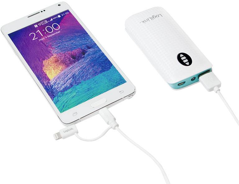 Eine Powerbank lädt ein Smartphone über ein USB-Kabel. Das Smartphone zeigt '21:00' auf dem Bildschirm.