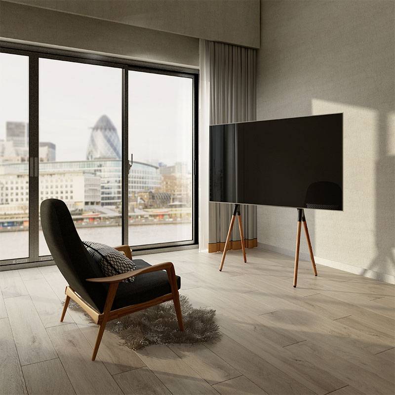 Zimmer mit einem schwarzen Sessel und Flachbildfernseher, Holzboden, großen Fenstern mit Blick auf die Stadt und modernen Gebäuden im Hintergrund.