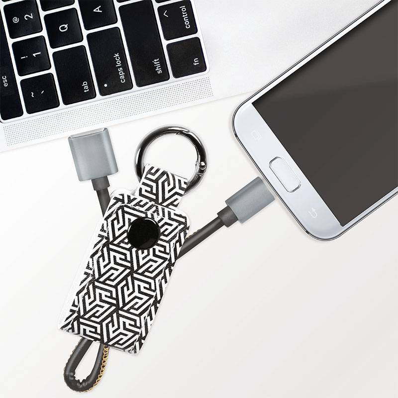 Schlüsselanhänger mit geometrischem Muster, verbunden mit einem Kabel, das zwischen einem Laptop und einem Smartphone angeschlossen werden kann.