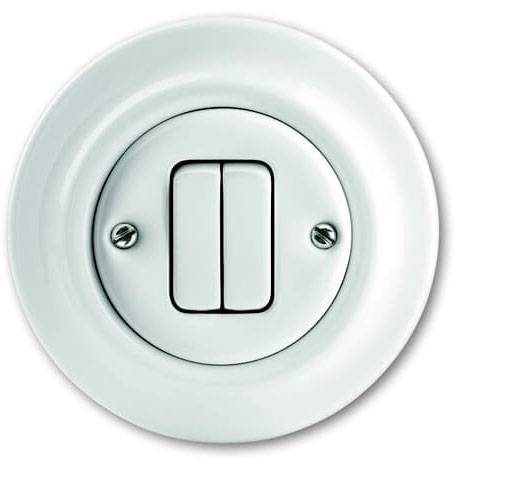 Ein runder weißer Lichtschalter mit zwei Kippschaltern, montiert auf einer weißen Platte. Flache, schlichte Gestaltung.