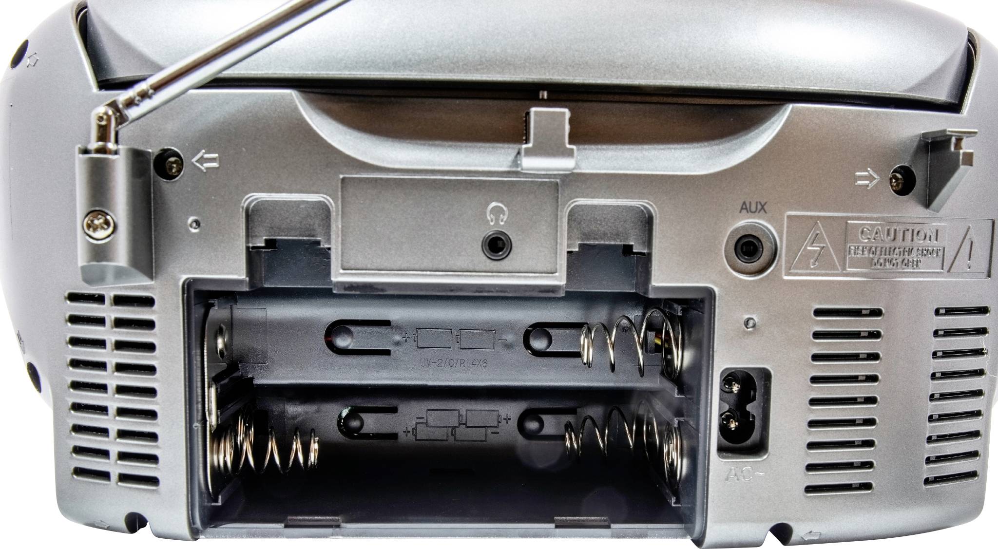Die Rückseite eines silbernen Radio-CD-Players zeigt geöffnete Batteriefächer, Anschlüsse und einen ausgeklappten Antennenstab.