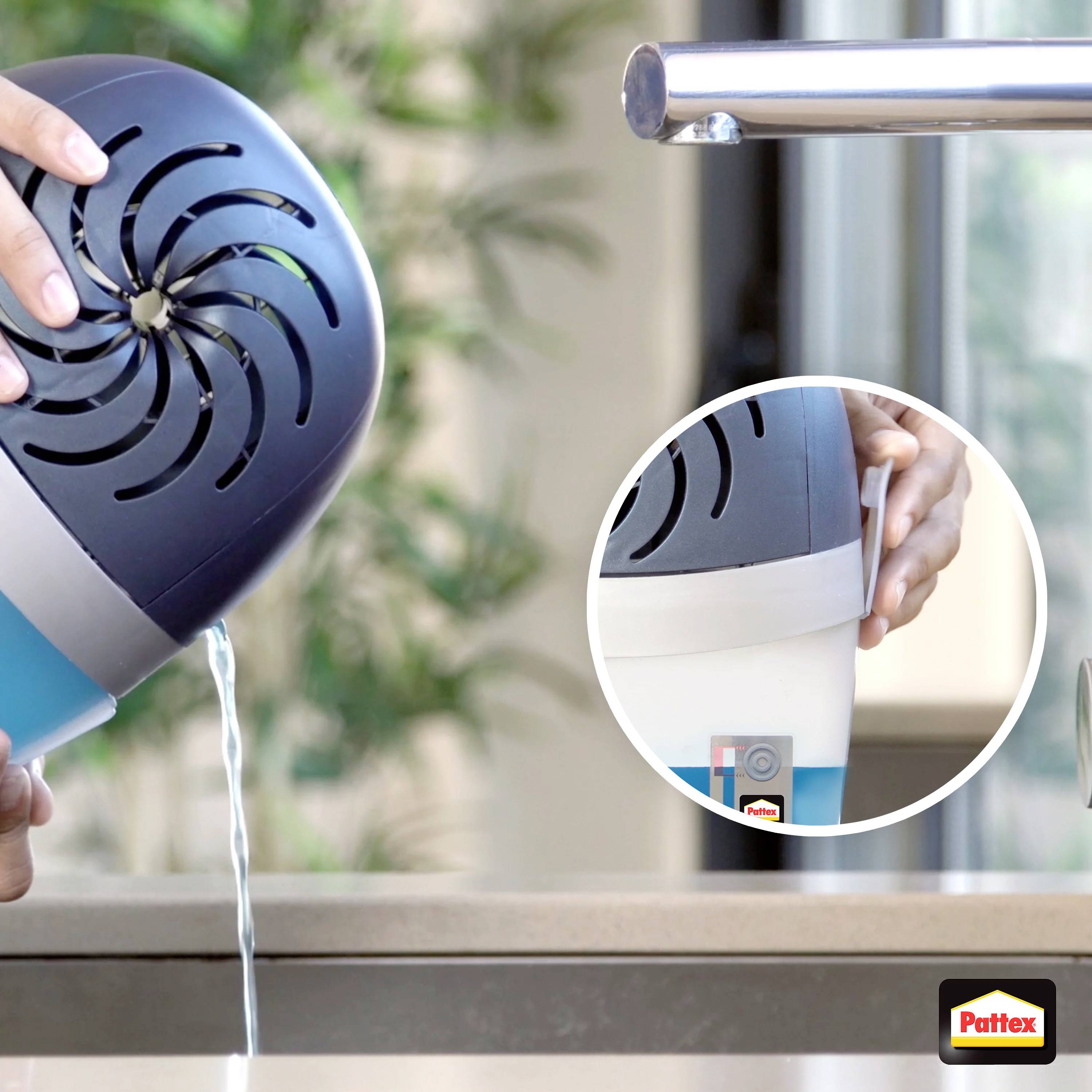 Ein Entfeuchter wird über einem Waschbecken entleert. Der Entfeuchter ist in der Nahaufnahme zu sehen, mit einer Hand, die hält.