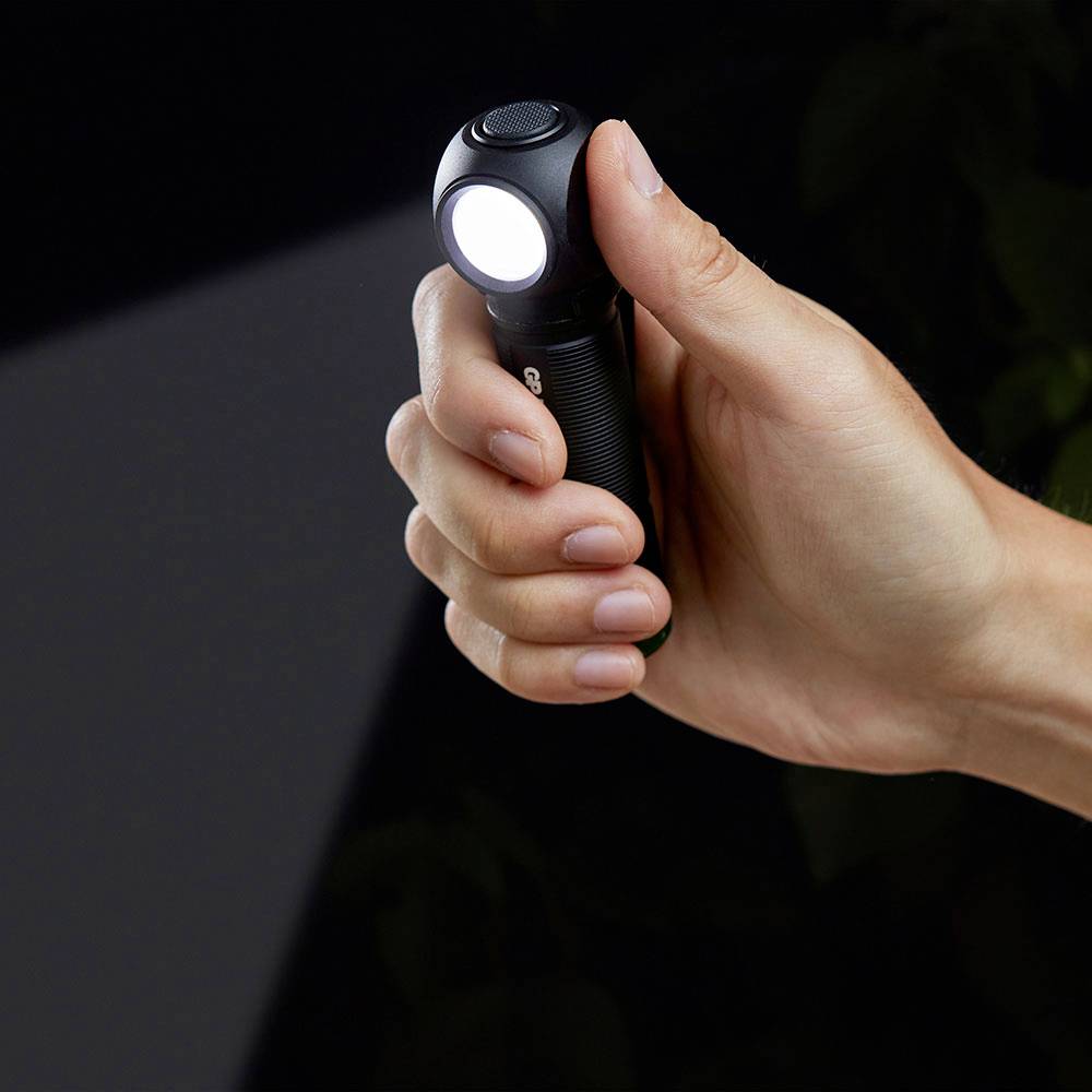 Hand hält eine eingeschaltete kleine Taschenlampe vor einem dunklen Hintergrund.