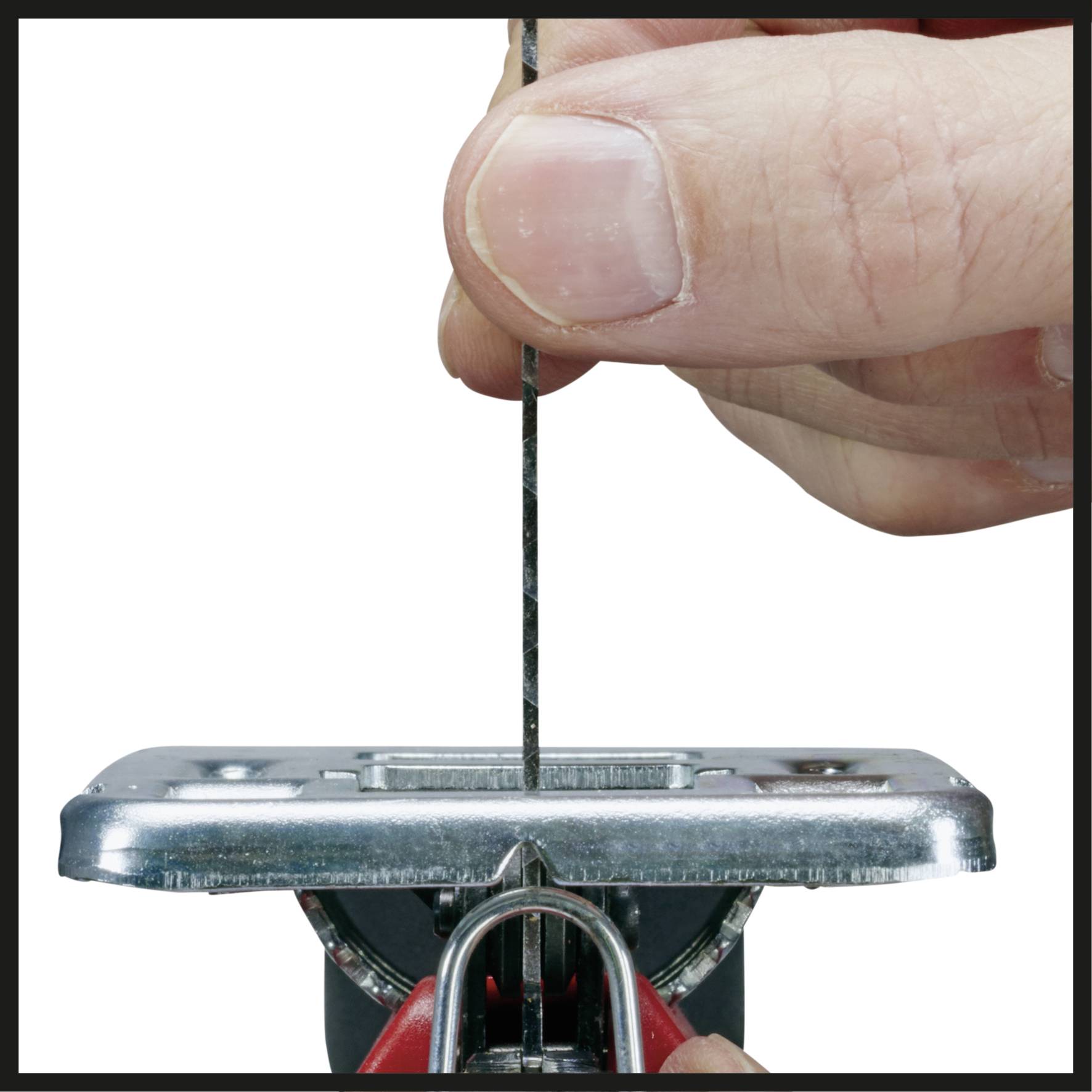 Eine Hand hält eine dünne Metallnadel vertikal über eine Metallplatte mit einem kleinen rechteckigen Loch.