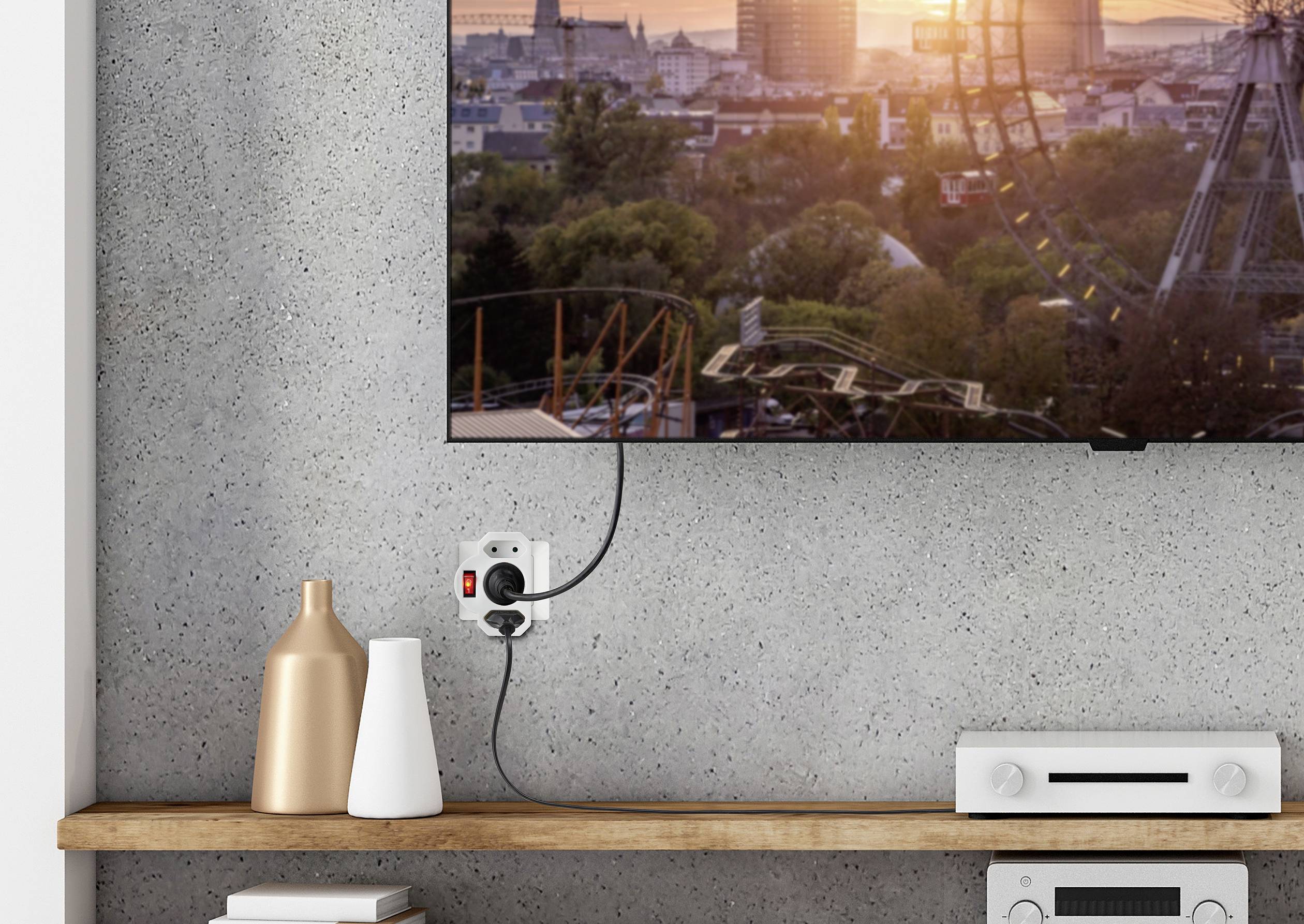 Ein Fernseher an der Wand zeigt eine Stadtlandschaft bei Sonnenuntergang. Darunter ein Regal mit Vasen und einem Elektronikgerät.