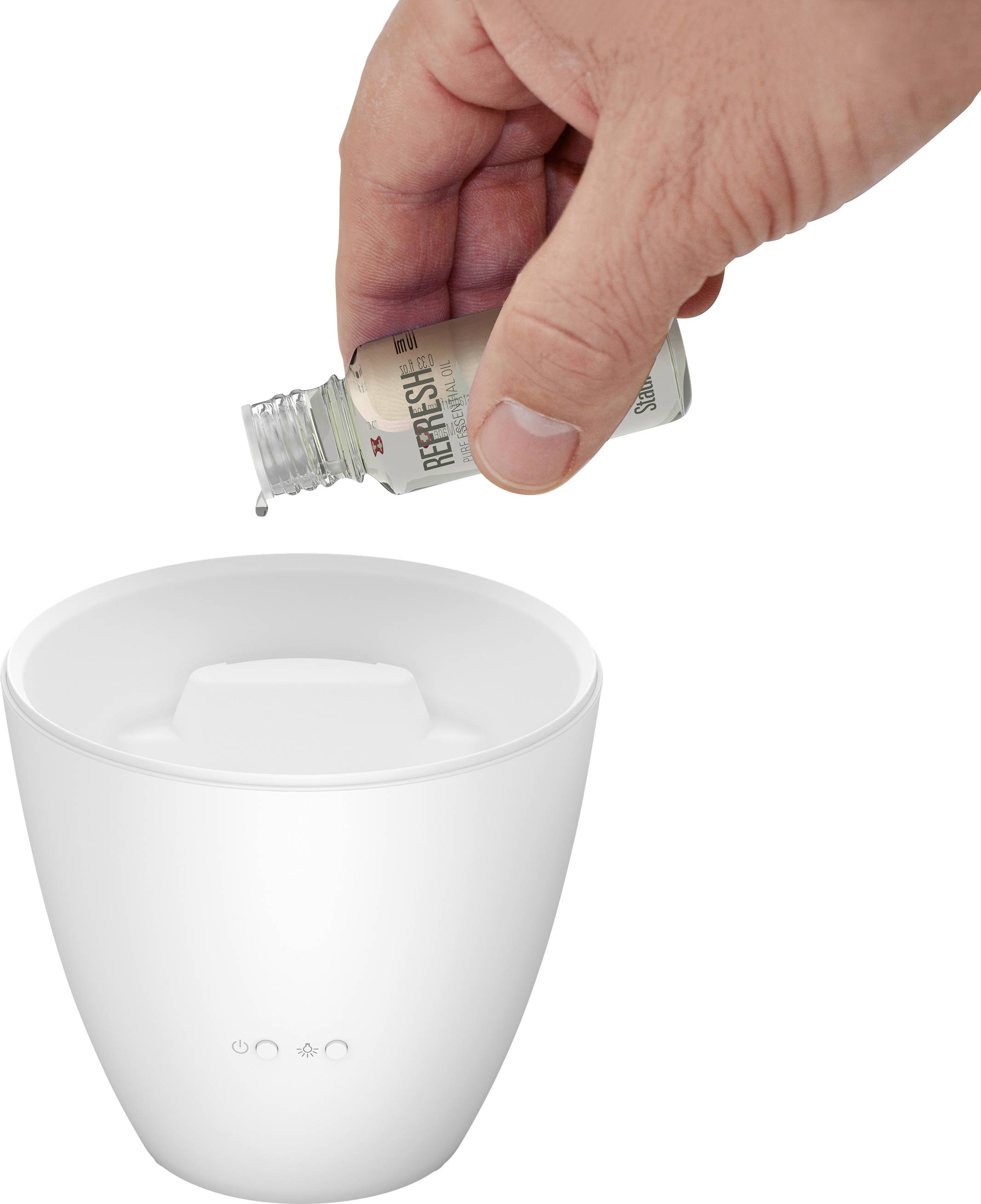 Eine Hand gießt ätherisches Öl in einen weißen Diffusor.