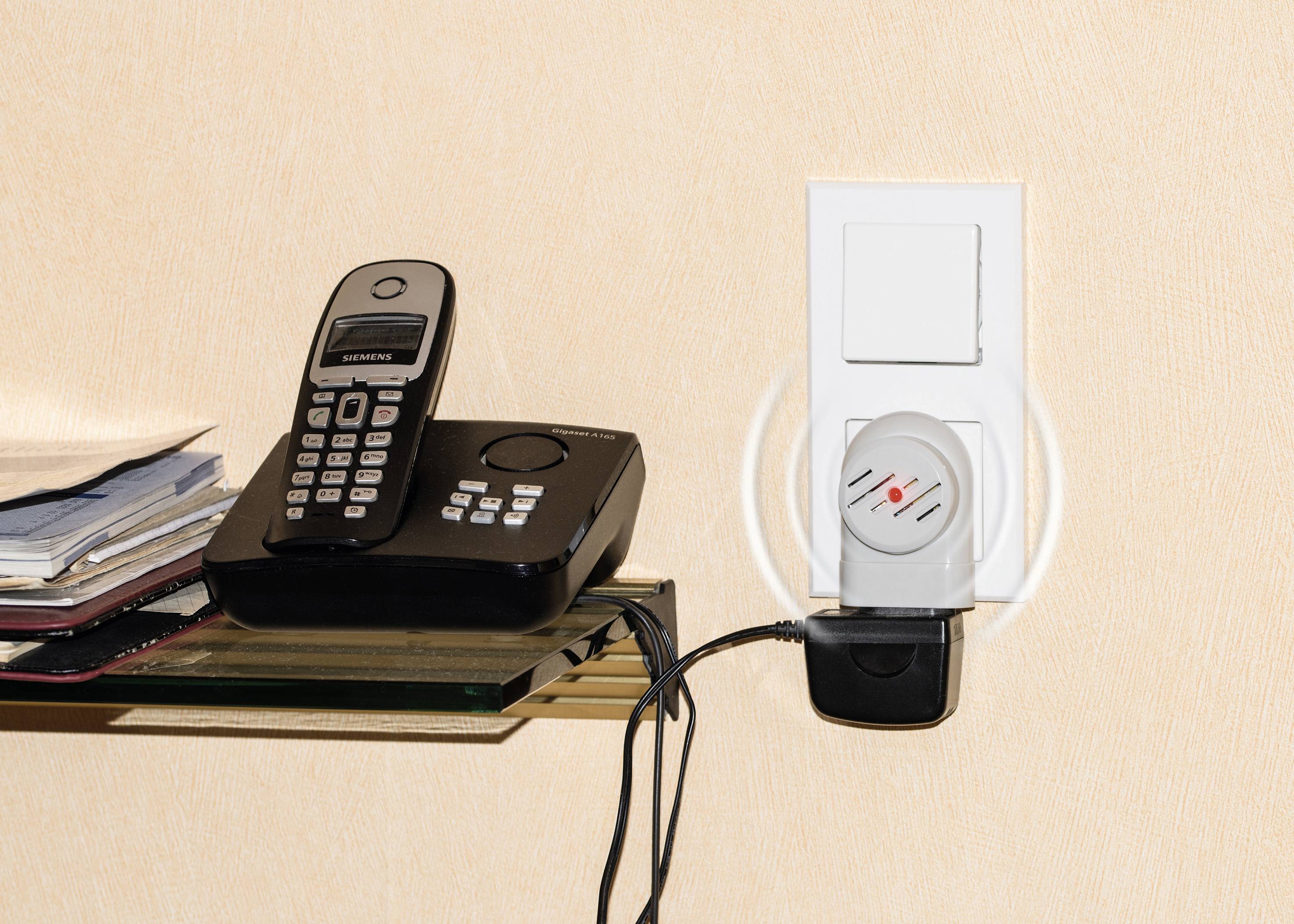 'Europäisches Funkenmelder-Überwachungssystem' zeigt ein Telefon mit Basisstation neben einer Steckdose mit angeschlossenem Geräten.