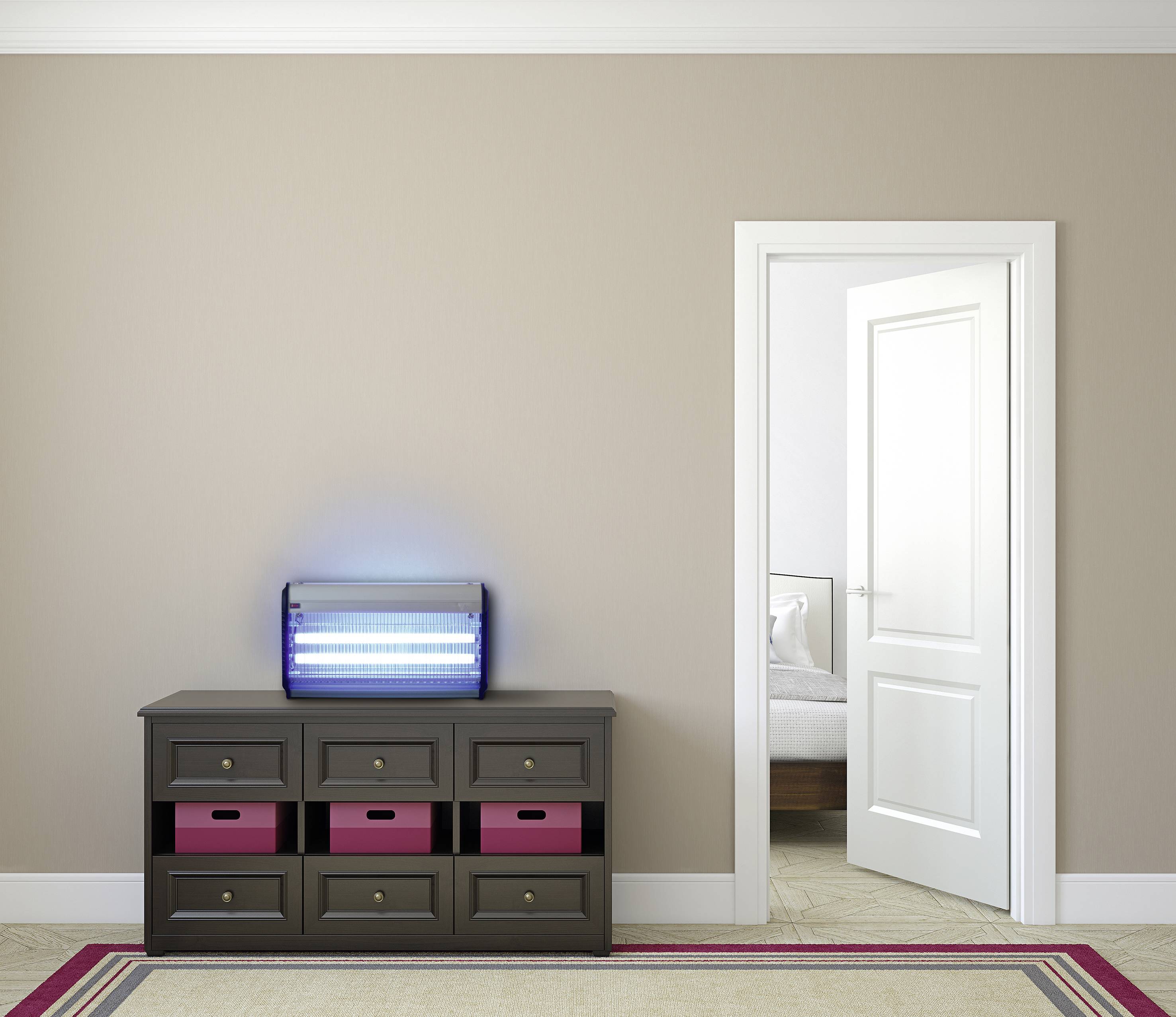 Ein modern eingerichtetes Zimmer mit einer offenen Tür zu einem Schlafzimmer. Auf der Kommode steht eine leuchtende UV-Lampe.