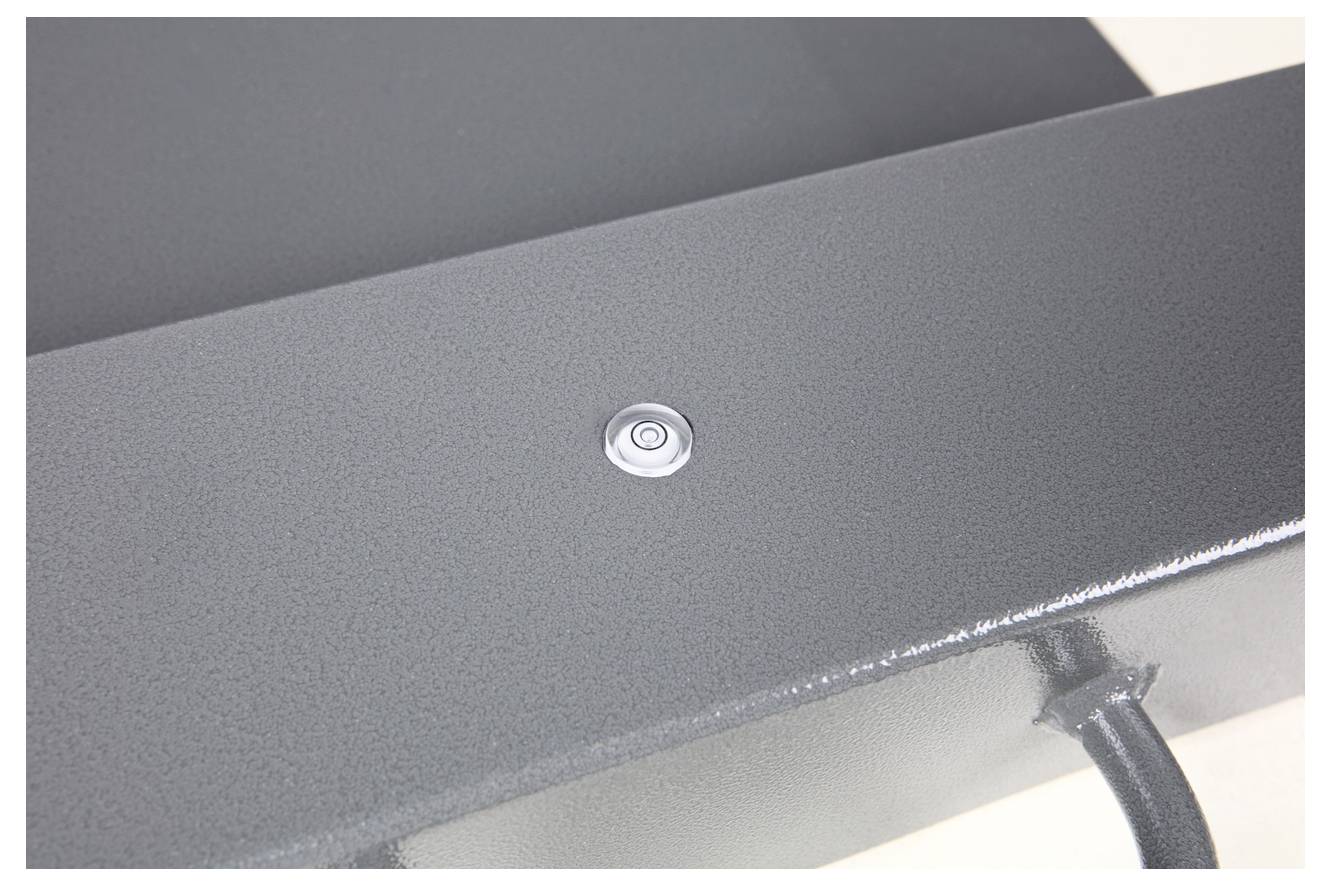 Ein kleiner, runder Metallknopf auf einer grau-schwarzen Metalloberfläche.