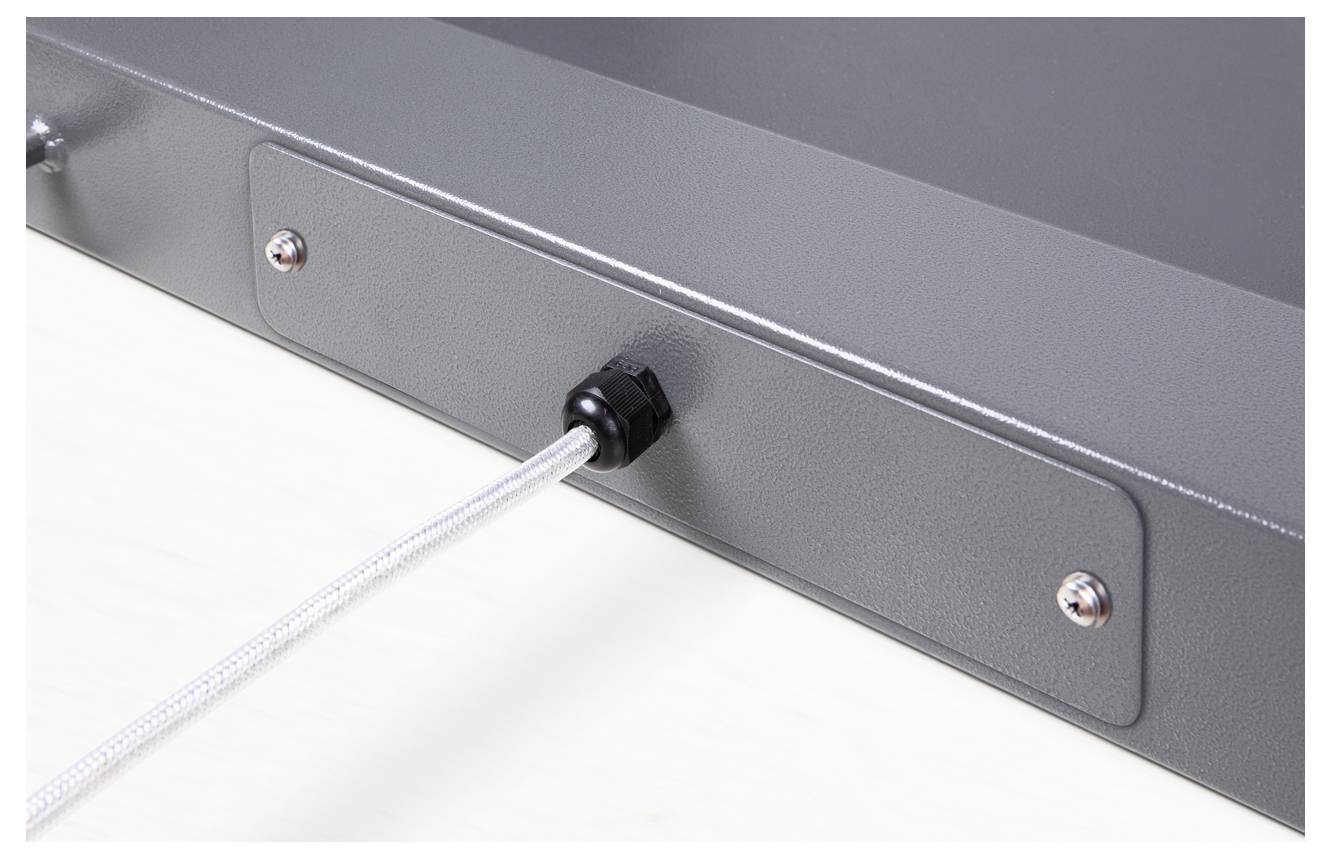 Graues Metallgehäuse mit einem befestigten weißen Kabel, das durch einen schwarzen Anschluss geführt wird. Schrauben sichtbar.