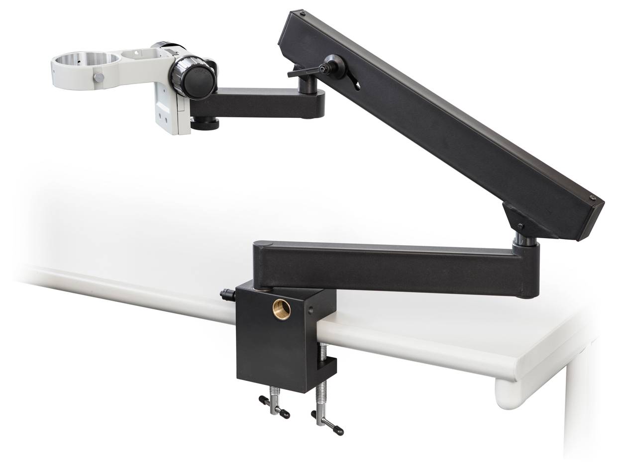 Ein schwarzer, verstellbarer Monitorarm ist an einem weißen Schreibtisch befestigt. Der Arm hat mehrere Gelenke für flexible Positionierung.