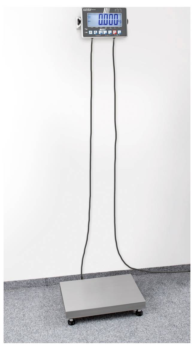 Waage mit grauem Plattformboden und digitalem Display an der Wand, verbunden durch zwei lange Kabel. Anzeige zeigt '000.0'.