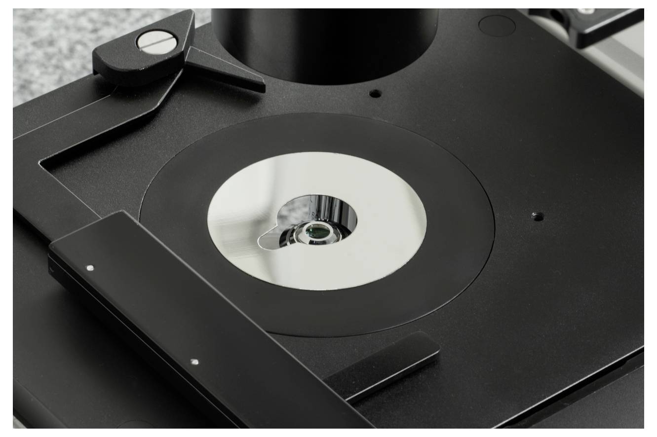 Nahaufnahme eines Mikroskops mit einer metallischen Probenhalterung in der Mitte.