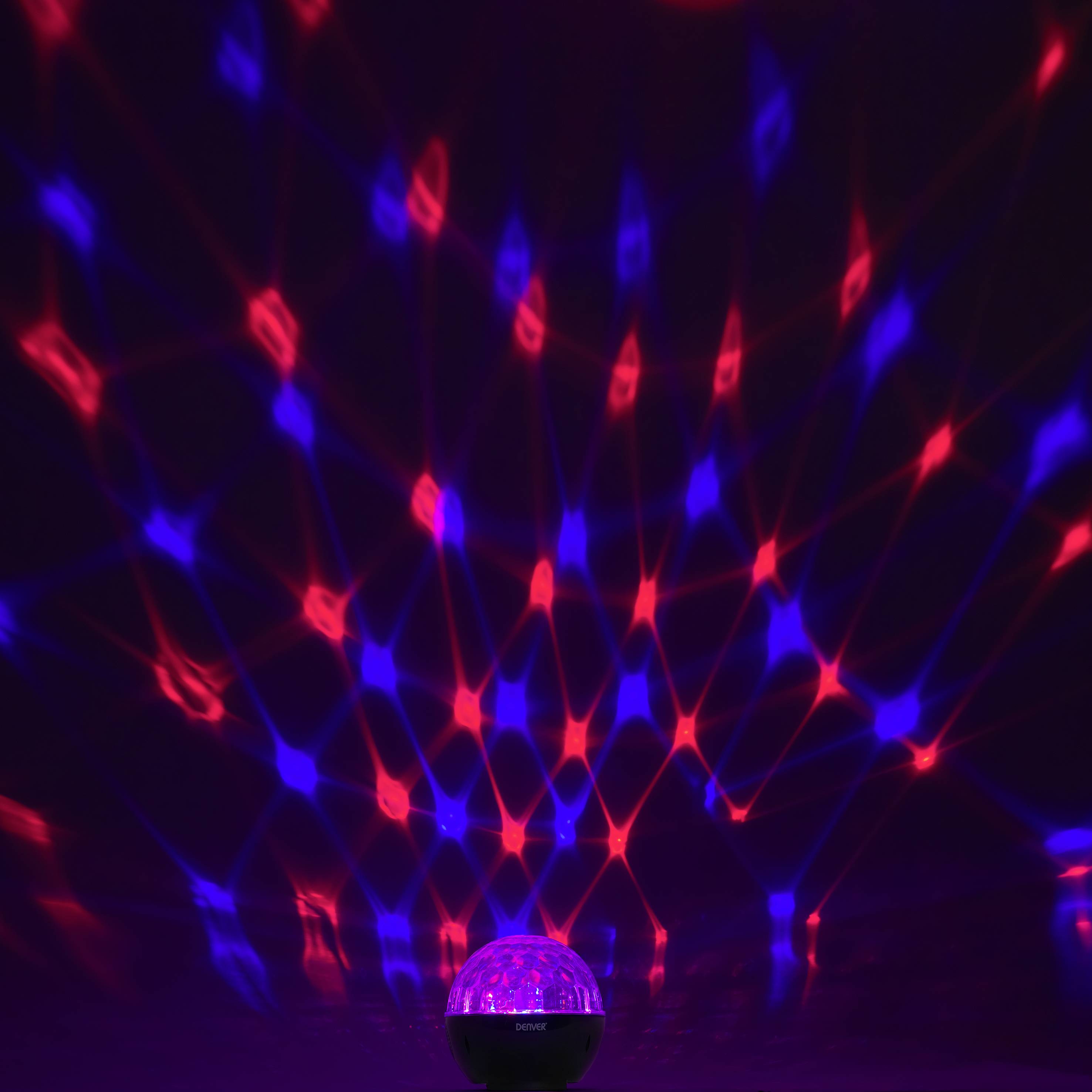 Eine leuchtende Kugellampe projiziert rote und blaue Lichter in einem Gittermuster an die Wände eines dunklen Raumes.