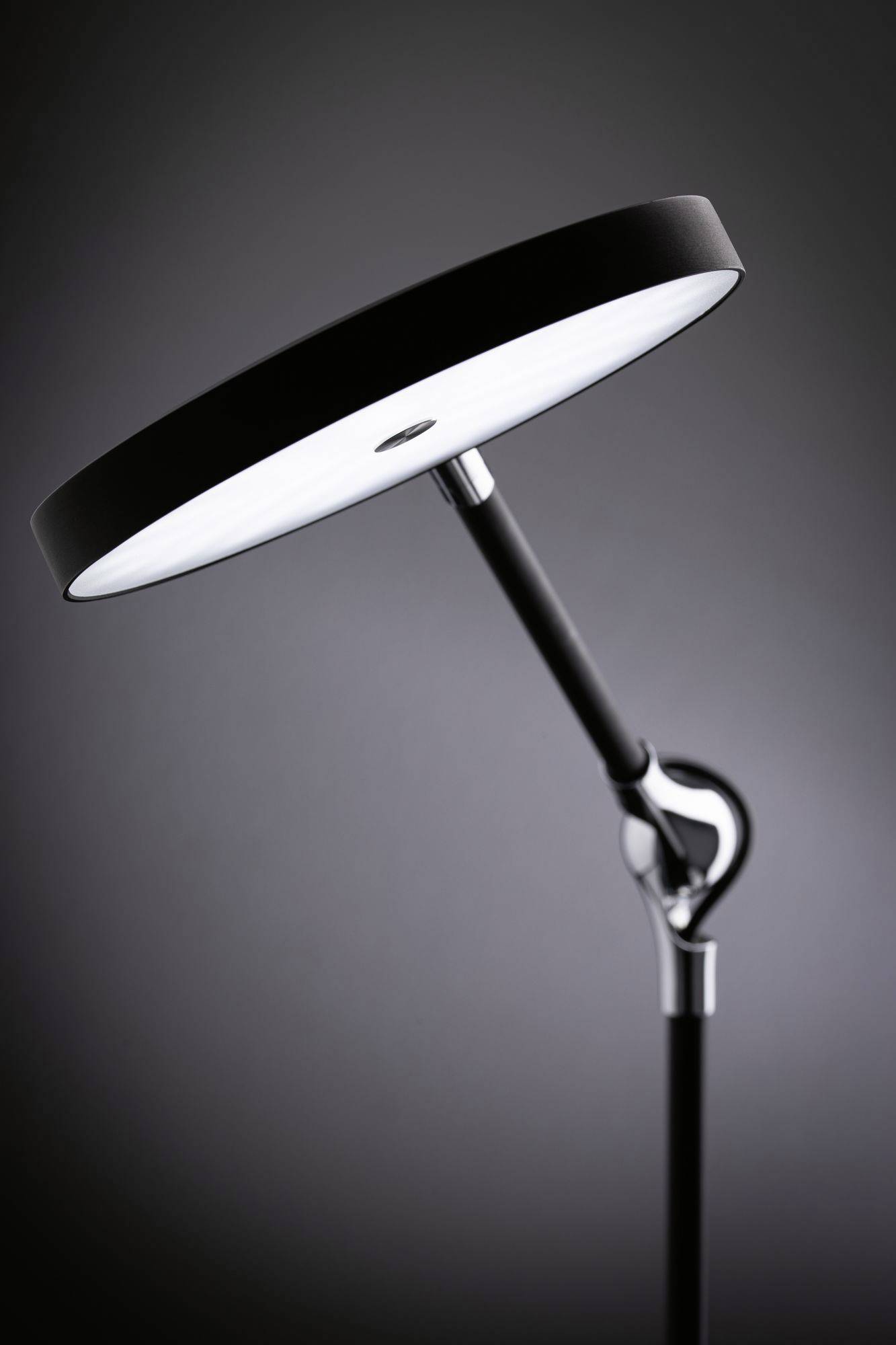 Stehlampe mit rundem weißem Schirm und schwarzem Ständer, moderne Designsprache, in einem schlicht beleuchteten Raum dargestellt.