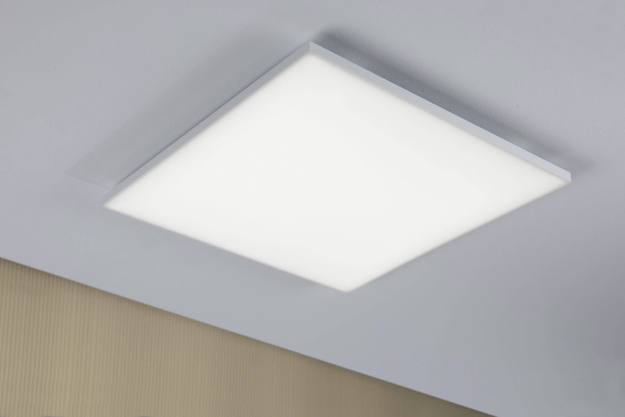 Quadratische LED-Deckenleuchte, gleichmäßig beleuchtet, montiert an einer weißen Decke über einem beigen, strukturierten Hintergrund.