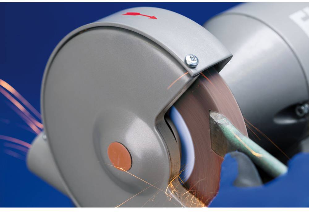 Nahaufnahme einer Schleifmaschine, die Funken erzeugt, während sie ein Metallwerkstück bearbeitet. Die Maschine hat einen blauen Hintergrund.