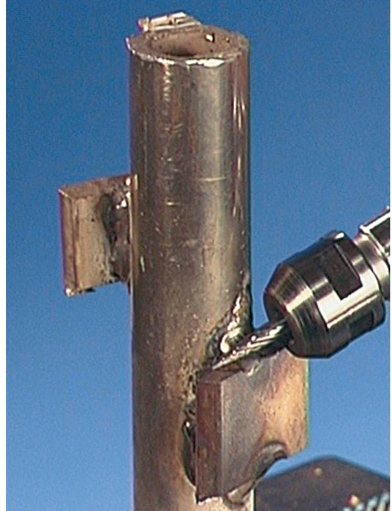 Metallbohrer bearbeitet vertikales Rohr, erzeugt Loch. Metallkonstruktionsprozess in Aktion.