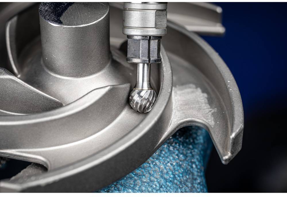 Eine Metallfräse bearbeitet präzise ein rotierendes Turbinenrad. Großer Fokus auf die Fräsbewegung und das Metallwerkstück.