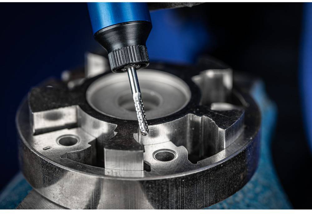 Nahaufnahme einer CNC-Fräsmaschine, die ein Metallstück bearbeitet. Der Fräskopf ist präzise ausgerichtet auf das Werkstück.