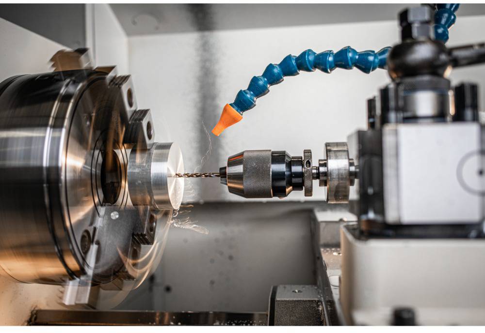 Eine Drehmaschine bearbeitet ein Metallstück; Bohrer in Aktion, Metallspäne fliegen. Arbeitsplatz in einer Werkstatt.