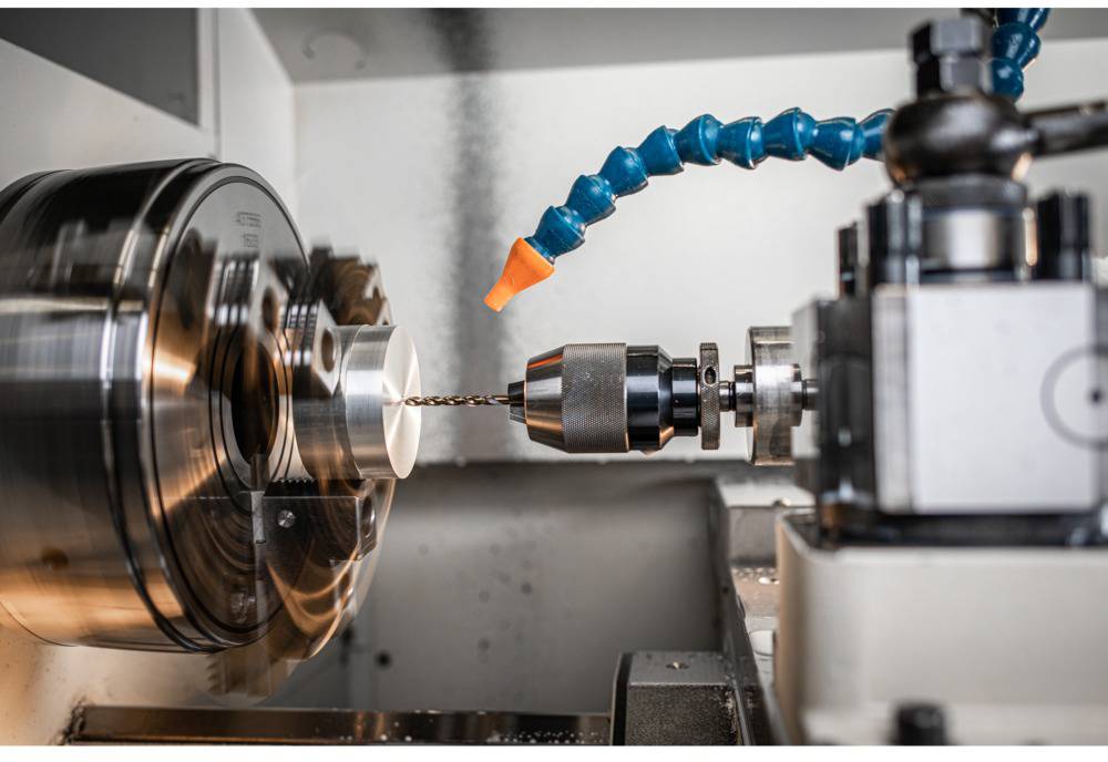 Eine Drehmaschine bohrt präzise ein Metallstück. Ein orangefarbenes Kühlmittelrohr hält den Bohrprozess kühl.