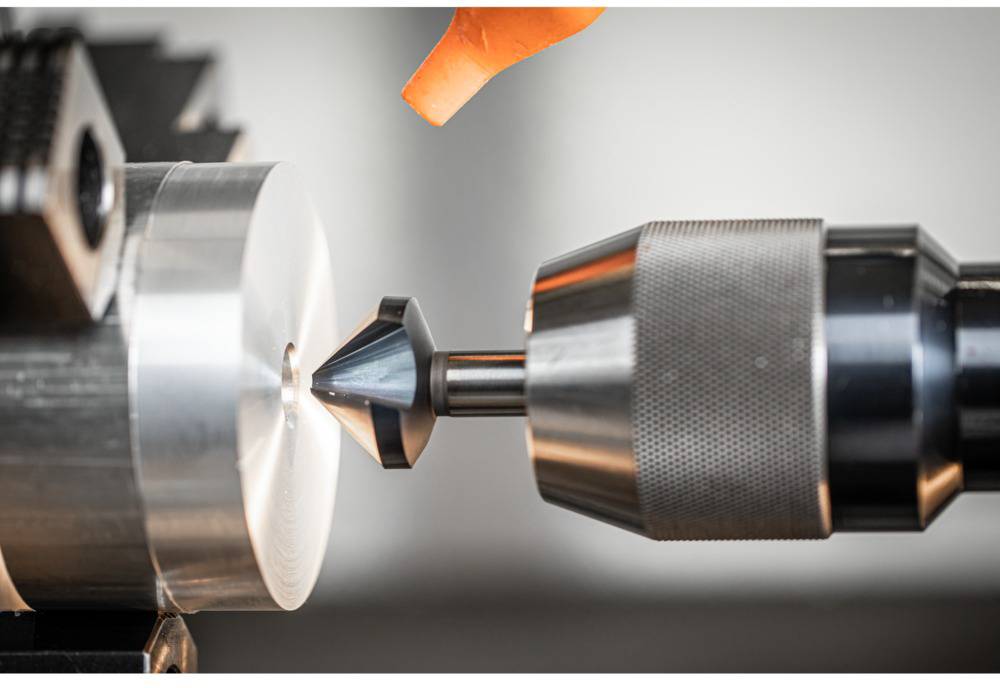 Ein Bohrer bearbeitet ein rundes Metallstück auf einer Drehbank in einer Werkstatt, während funken sprühen.