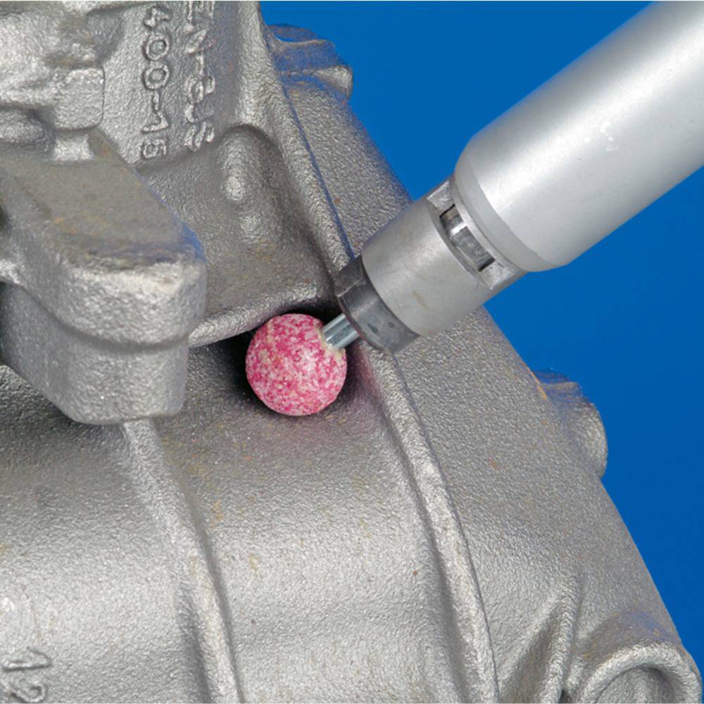 Ein metallisches Werkstück wird mit einem rotierenden Schleifaufsatz bearbeitet, um die Oberfläche zu glätten.