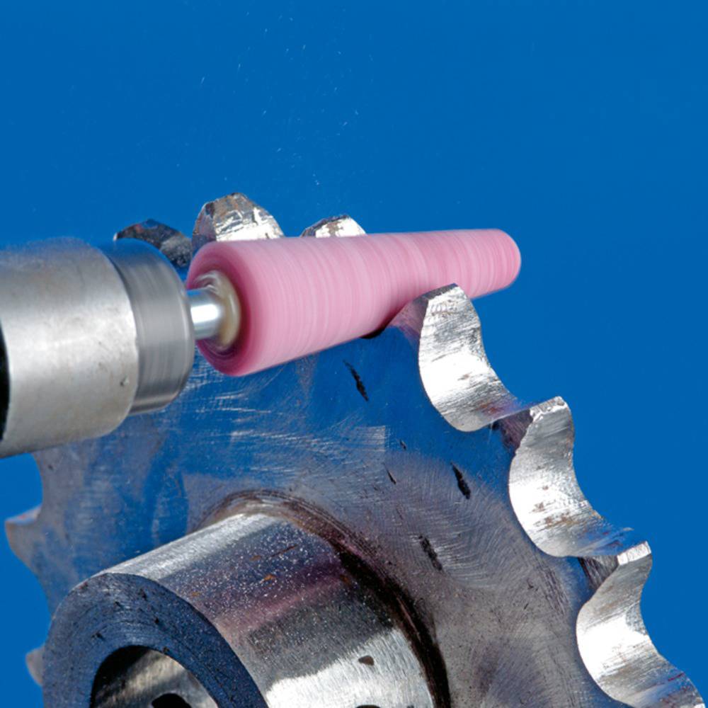 Ein Schleifstein bearbeitet die scharfe Kante eines Sägeblatts in Nahaufnahme, zeigt Werkzeugarbeit und Abnutzung.