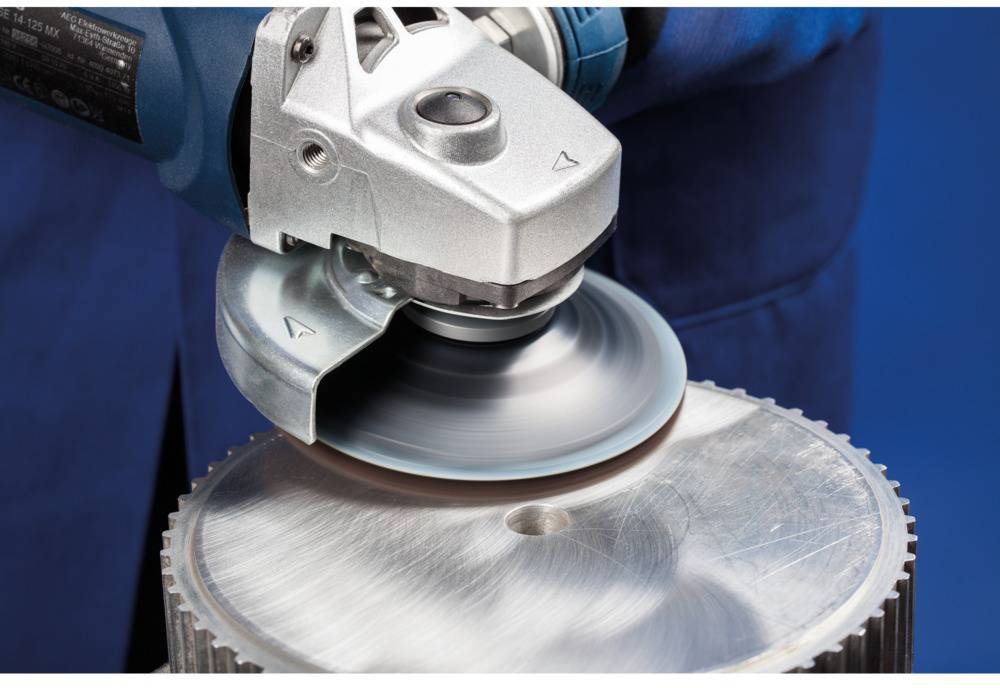 Eine Person verwendet einen Winkelschleifer, um die Oberfläche einer Metallplatte zu polieren. Funken entstehen durch den Schleifvorgang.