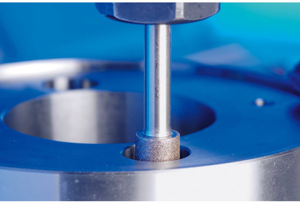 Maschine beim Schleifen eines Metallteils, Nahaufnahme des Schleifkopfes in Aktion. Präzise Bearbeitung, metallische Oberfläche.