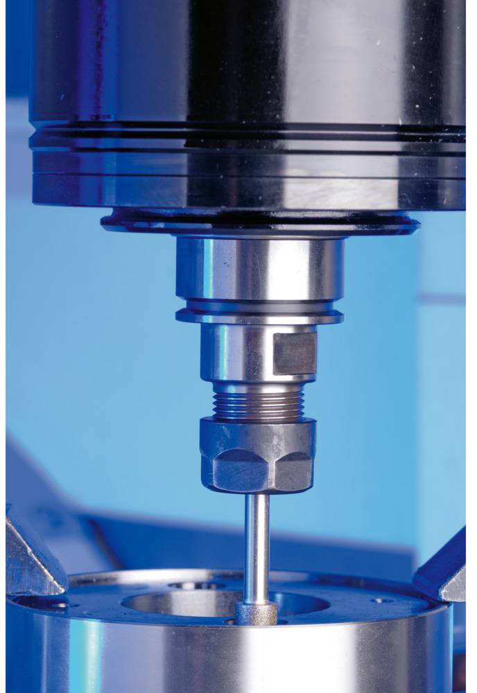 Eine Maschine bearbeitet ein Metallstück in Nahaufnahme. Die Umgebung leuchtet blau.