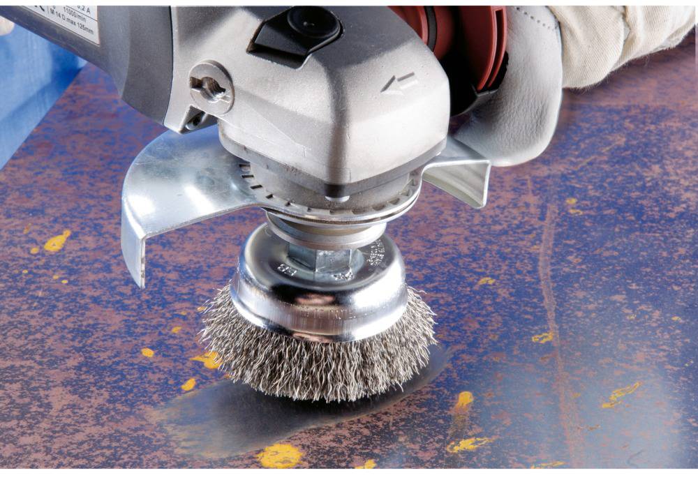 Eine rotierende Drahtbürste wird verwendet, um Rost von einer Metalloberfläche zu entfernen.